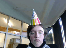 a young man wearing a colorful party hat with polka dots