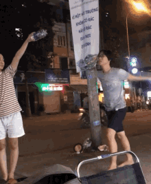 a man holds up a bottle of water in front of a sign that says " ve mot nc truong "