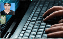 a person is typing on a laptop keyboard with a picture of a man in the background