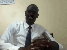 a man wearing a white shirt and blue tie smiles for the camera