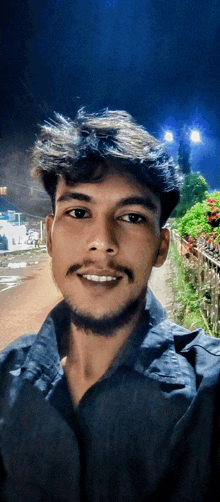 a young man with a beard and mustache smiles for the camera