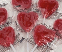 a bunch of heart shaped lollipops in plastic wrappers .