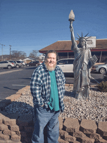 a man in a plaid shirt stands in front of a statue of the statue of liberty