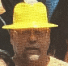 a man wearing a yellow hard hat looks at the camera with his eyes closed