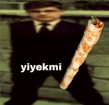 a man in a suit and tie is holding a burrito in front of a sign that says yiyekmi