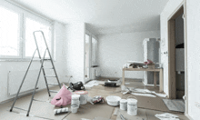 an empty room with a ladder and paint buckets on the floor