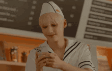 a man wearing a sailor hat is looking at his cell phone