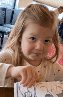 a little girl is sitting at a table with a piece of paper in front of her