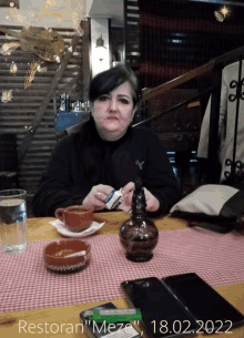 a woman sits at a table in a restaurant with the date 18.02.2022 on the bottom right