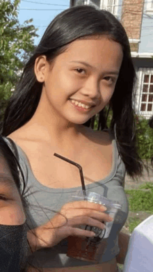 a young girl is holding a cup with a straw and smiling for the camera