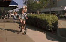 a boy is riding a bike down a sidewalk in front of a store that says ' abercrombie ' on it