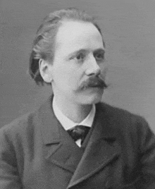 a black and white photo of a man with a mustache wearing a suit and tie