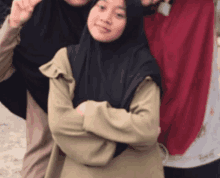 a woman wearing a black hijab is posing for a picture with two other women