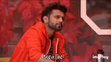 a man in a red jacket says breathe in front of a red background