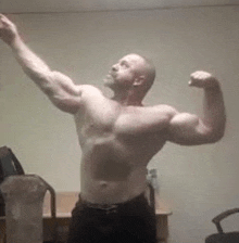 a shirtless man is flexing his muscles in a room in front of a table .