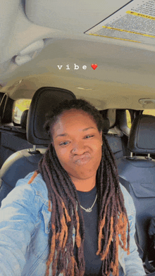 a woman with dreadlocks is taking a selfie in the back seat of a car with the words vibe above her