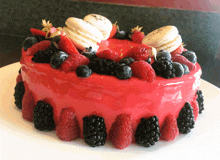 a red cake with berries and macaroons on top