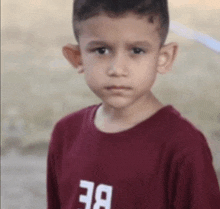 a young boy wearing a maroon shirt that says be