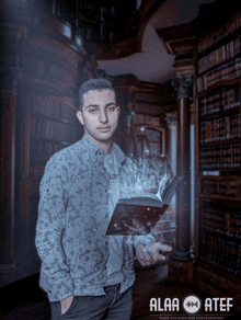 a man holding a book in a library with alaa atef in the corner