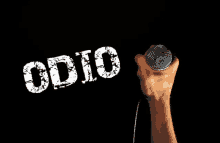 a hand is holding a microphone in front of a black background that says " odio "