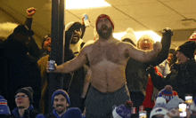 a shirtless man stands in a crowd of people holding a can of budweiser