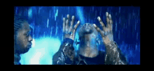 a man is standing in the rain with his hands in the air and his face covered in water .