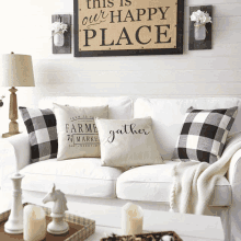 a white couch with black and white pillows and a sign that says this is our happy place