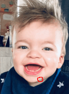 a baby is smiling with a red circle around his chin