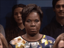 a woman in a floral dress is making a face in front of a group of people