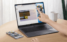 a person is using a laptop and a phone on a wooden table