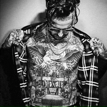 a man with a lot of tattoos on his chest is taking off his jacket