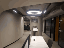 a long hallway with a circular light hanging from the ceiling above a desk