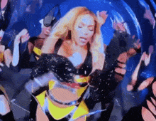 a woman in a yellow and black outfit is dancing in front of a crowd of people .