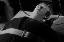 a black and white photo of frankenstein laying on a bed with his eyes closed