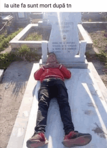 a man is laying on a grave in a cemetery