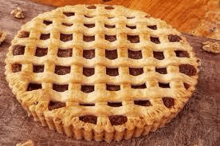 a pie with a lattice crust and walnuts on a wooden table .