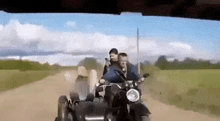 a man and a woman are riding a three wheeled vehicle on a dirt road .