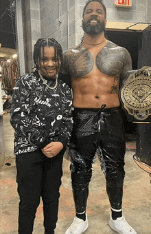 a man with a tattoo on his chest is standing next to a boy