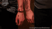 a man and a woman are holding hands with their wrists tattooed .