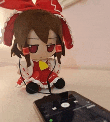 a stuffed doll wearing headphones sits next to a phone