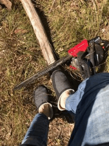 a person wearing slippers is sitting on the ground next to a chainsaw and an axe .