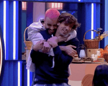 a man with pink hair is hugging another man in a room