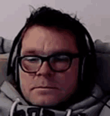 a man wearing glasses and headphones is sitting on a chair .