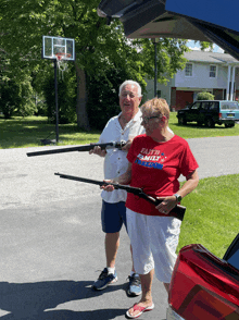 a man and a woman are holding guns and the woman is wearing a shirt that says faith family and freedom