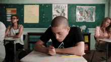 a boy sits at a desk in a classroom with a poster on the wall that says " i have a dream "