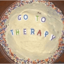 a cake with frosting and sprinkles that says " go to therapy "