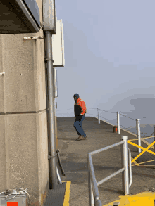 a man in a red jacket is walking on a concrete walkway