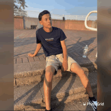 a young man wearing a hollister t-shirt sits on a set of steps