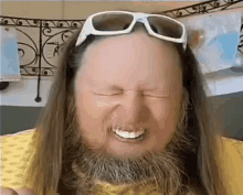 a man with a beard and long hair wearing sunglasses is making a funny face .