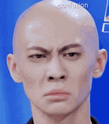 a close up of a bald man 's face with a confused expression .